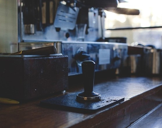 Coffee tamper on the coffee counter in front of a traditional coffee machine