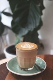 A cortado in a glass on a green saucer