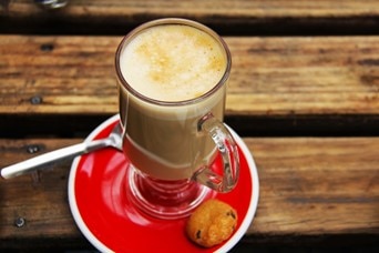 Flat white in a glass on a red saucer